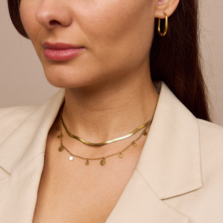 Eine filigrane Halskette mit schimmernden Plättchen, die das Licht reflektieren und ideal für vielseitige Looks von morgens bis abends geeignet ist – perfekt solo oder in Kombination mit anderen Schmuckstücken.