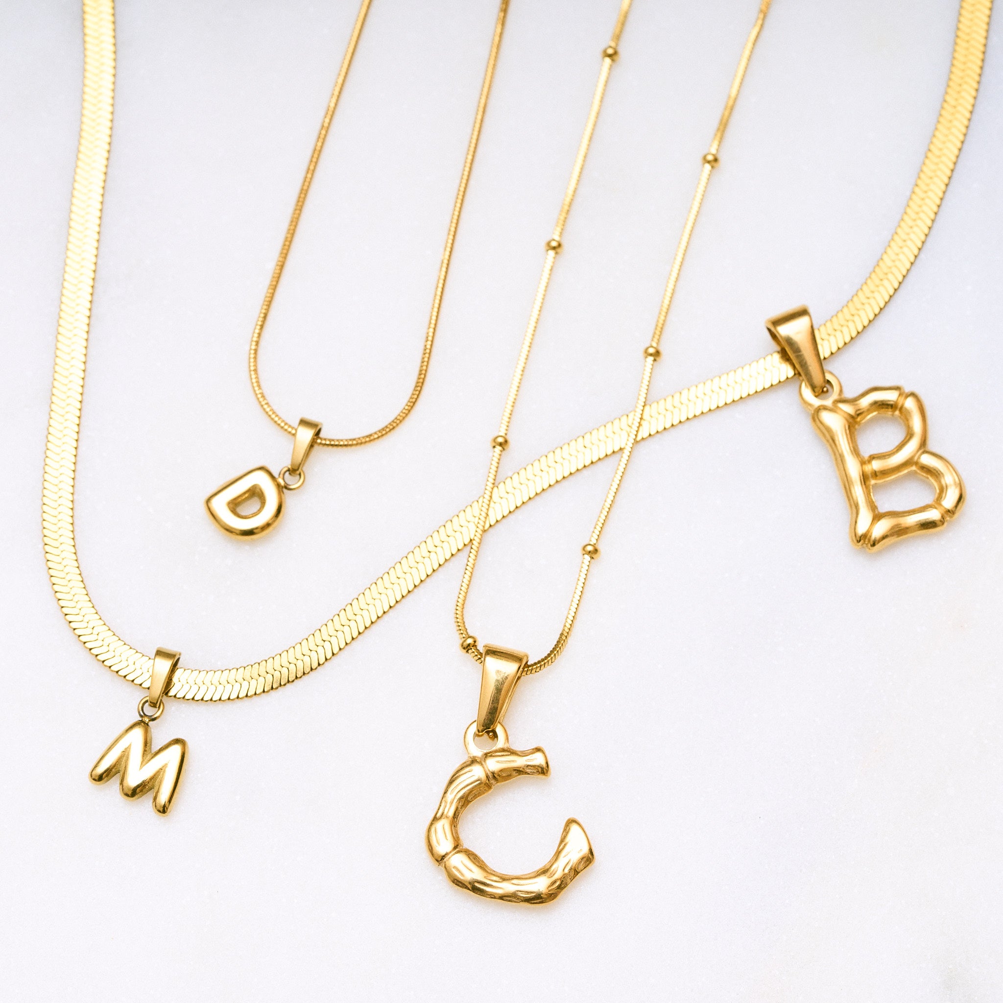 Einzelner Bamboo Bubble Buchstaben-Anhänger in glänzendem Gold – Vergoldeter Bubble Buchstaben Anhänger mit Bobby Kette auf weißem Hintergrund