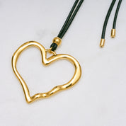 Trendige goldene Herzkette mit Schnurband und dem Schriftzug ‚LOVE‘. Der 90er-Jahre-inspirierte Schmuck bietet eine verspielte und kraftvolle Note, mit flexibler Verschlussmöglichkeit durch Knoten oder Schlaufe.