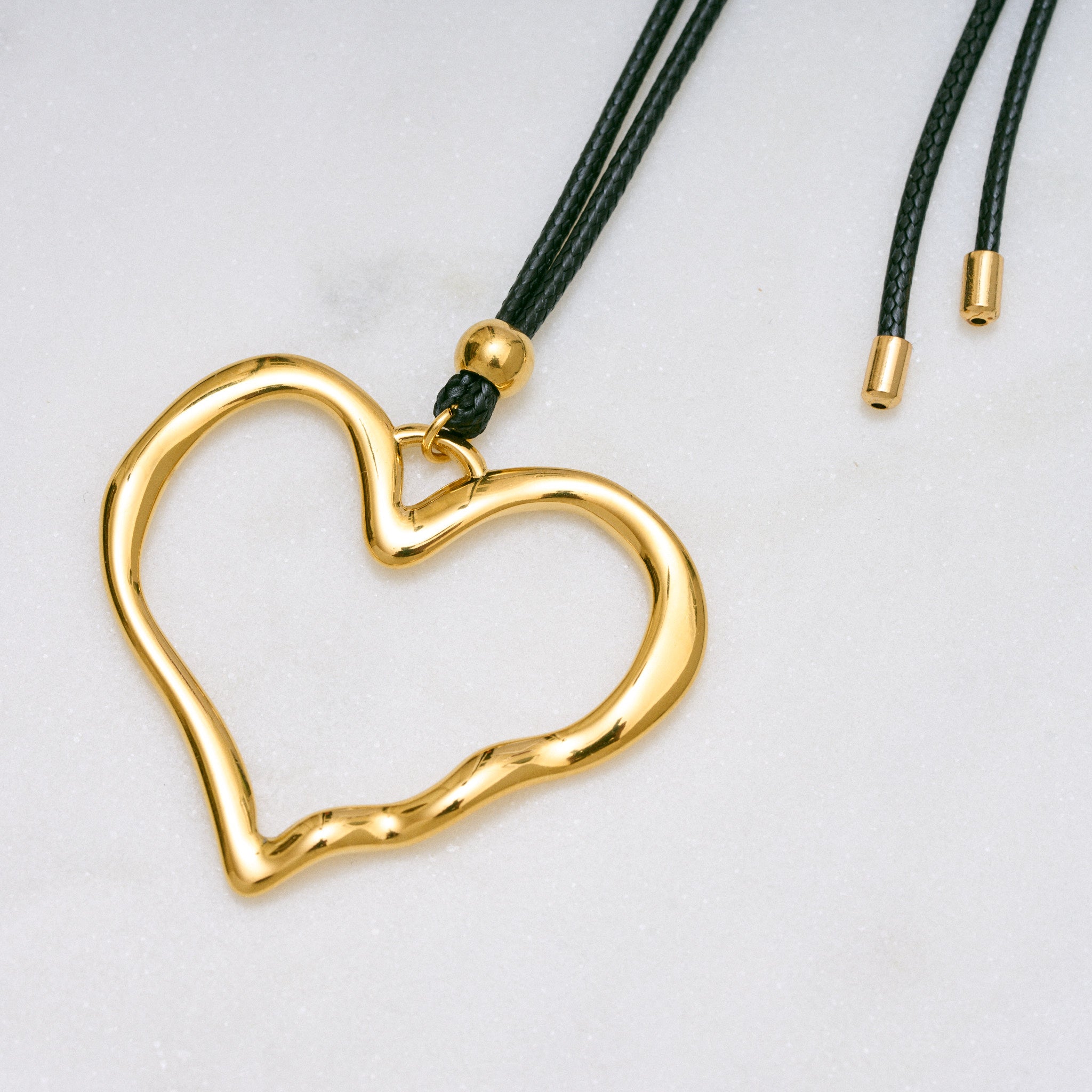 Trendige goldene Herzkette mit Schnurband und dem Schriftzug ‚LOVE‘. Der 90er-Jahre-inspirierte Schmuck bietet eine verspielte und kraftvolle Note, mit flexibler Verschlussmöglichkeit durch Knoten oder Schlaufe.