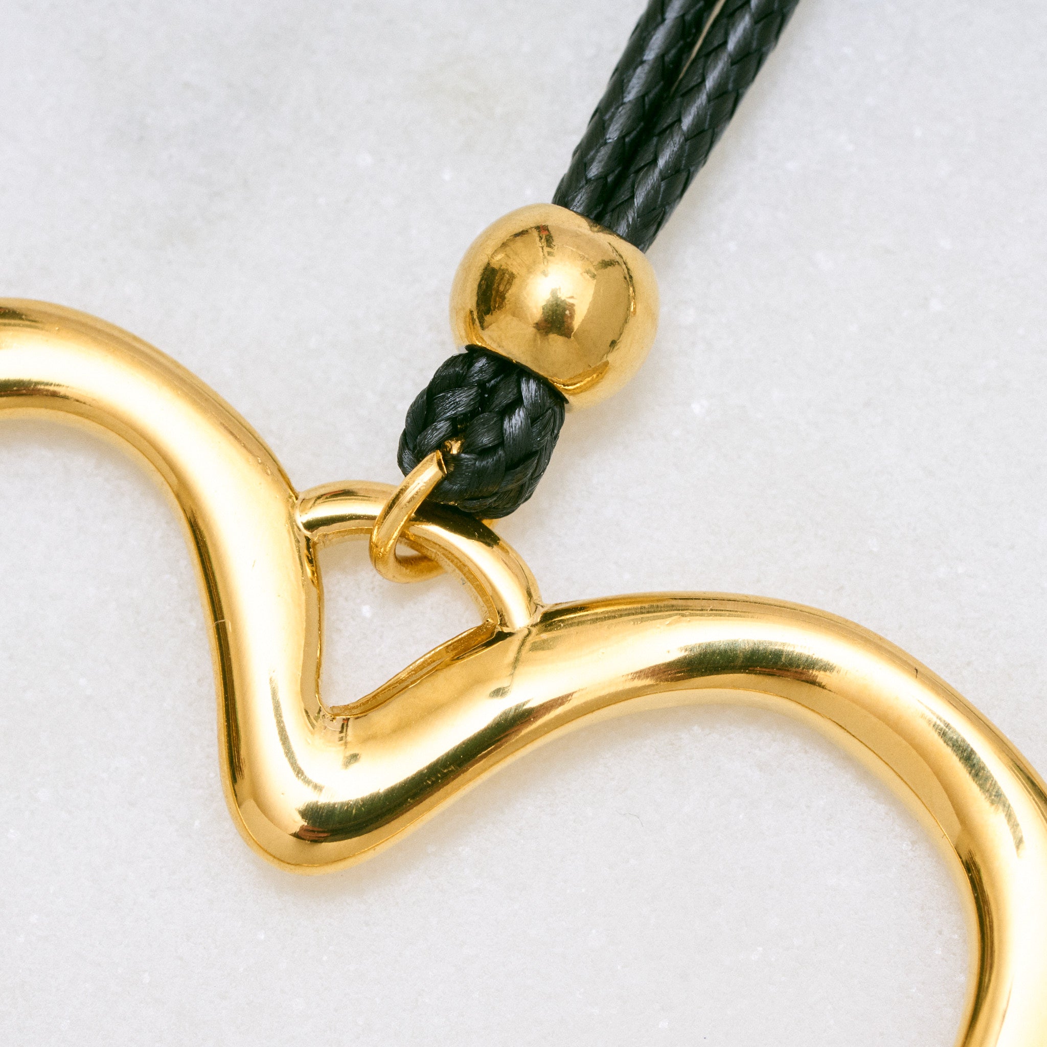 Trendige goldene Herzkette mit Schnurband und dem Schriftzug ‚LOVE‘. Der 90er-Jahre-inspirierte Schmuck bietet eine verspielte und kraftvolle Note, mit flexibler Verschlussmöglichkeit durch Knoten oder Schlaufe.