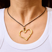 Trendige goldene Herzkette mit Schnurband und dem Schriftzug ‚LOVE‘. Der 90er-Jahre-inspirierte Schmuck bietet eine verspielte und kraftvolle Note, mit flexibler Verschlussmöglichkeit durch Knoten oder Schlaufe.