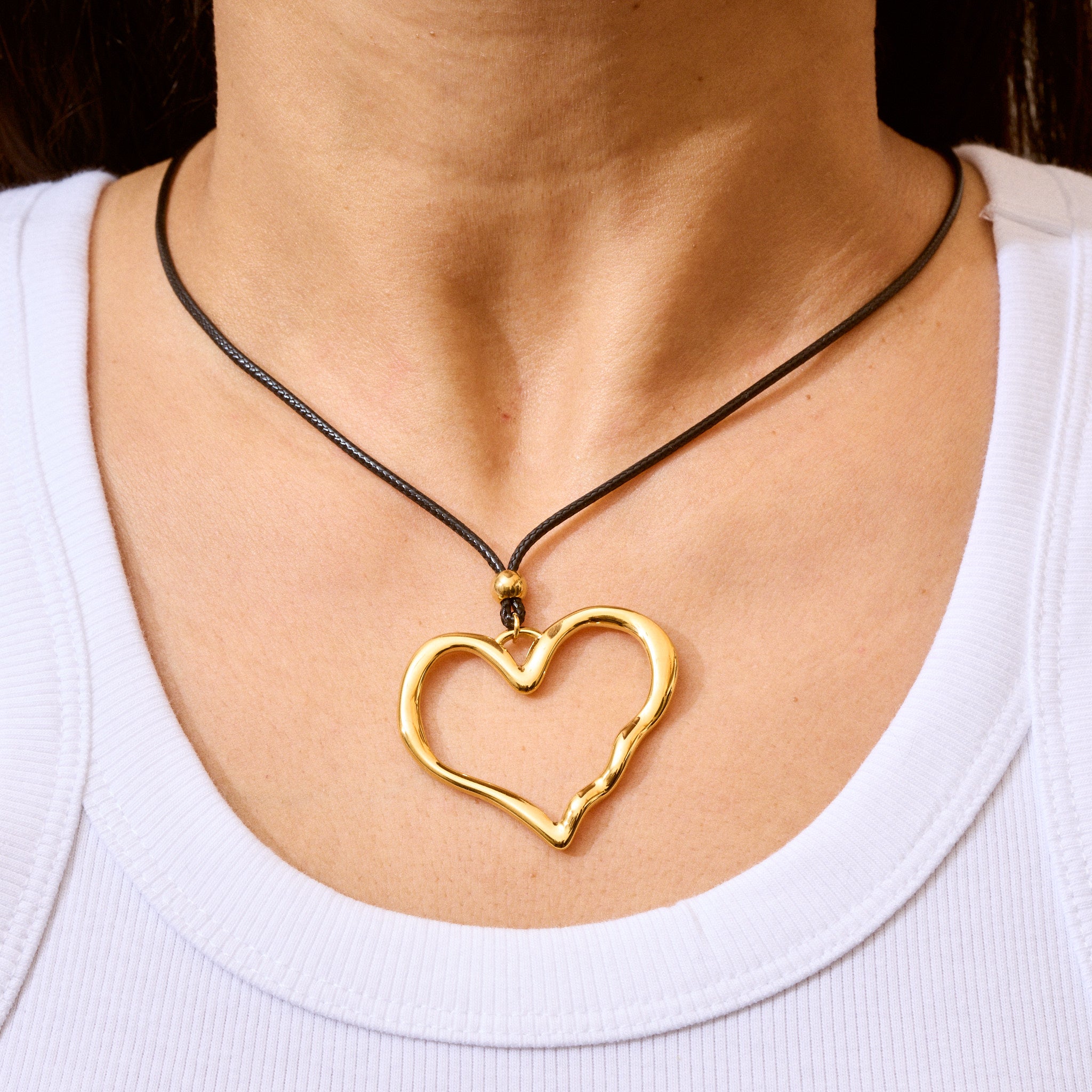 Trendige goldene Herzkette mit Schnurband und dem Schriftzug ‚LOVE‘. Der 90er-Jahre-inspirierte Schmuck bietet eine verspielte und kraftvolle Note, mit flexibler Verschlussmöglichkeit durch Knoten oder Schlaufe.