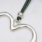 Trendige silberne Herzkette mit Schnurband und dem Schriftzug ‚LOVE‘. Der 90er-Jahre-inspirierte Schmuck bietet eine verspielte und kraftvolle Note, mit flexibler Verschlussmöglichkeit durch Knoten oder Schlaufe.