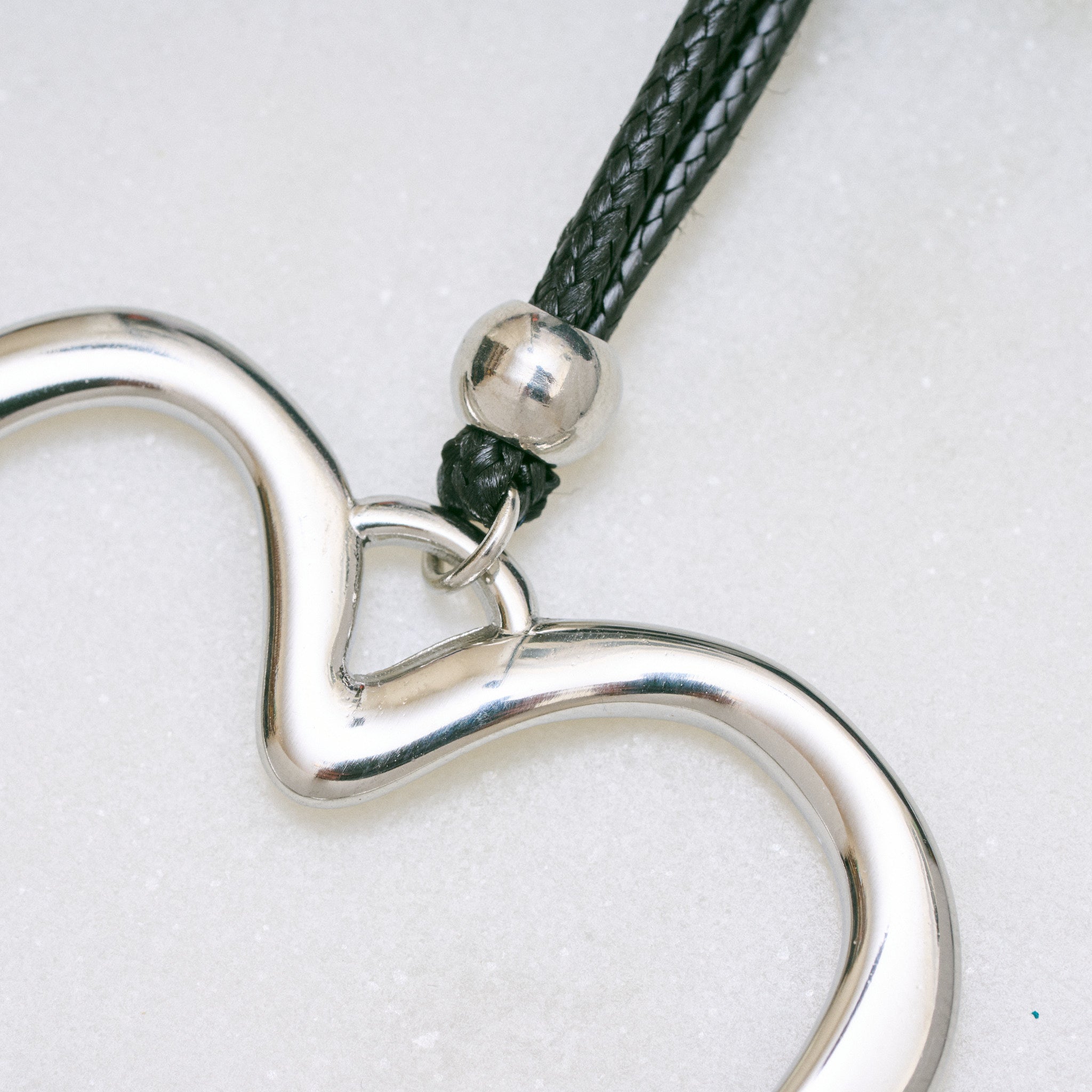 Trendige silberne Herzkette mit Schnurband und dem Schriftzug ‚LOVE‘. Der 90er-Jahre-inspirierte Schmuck bietet eine verspielte und kraftvolle Note, mit flexibler Verschlussmöglichkeit durch Knoten oder Schlaufe.