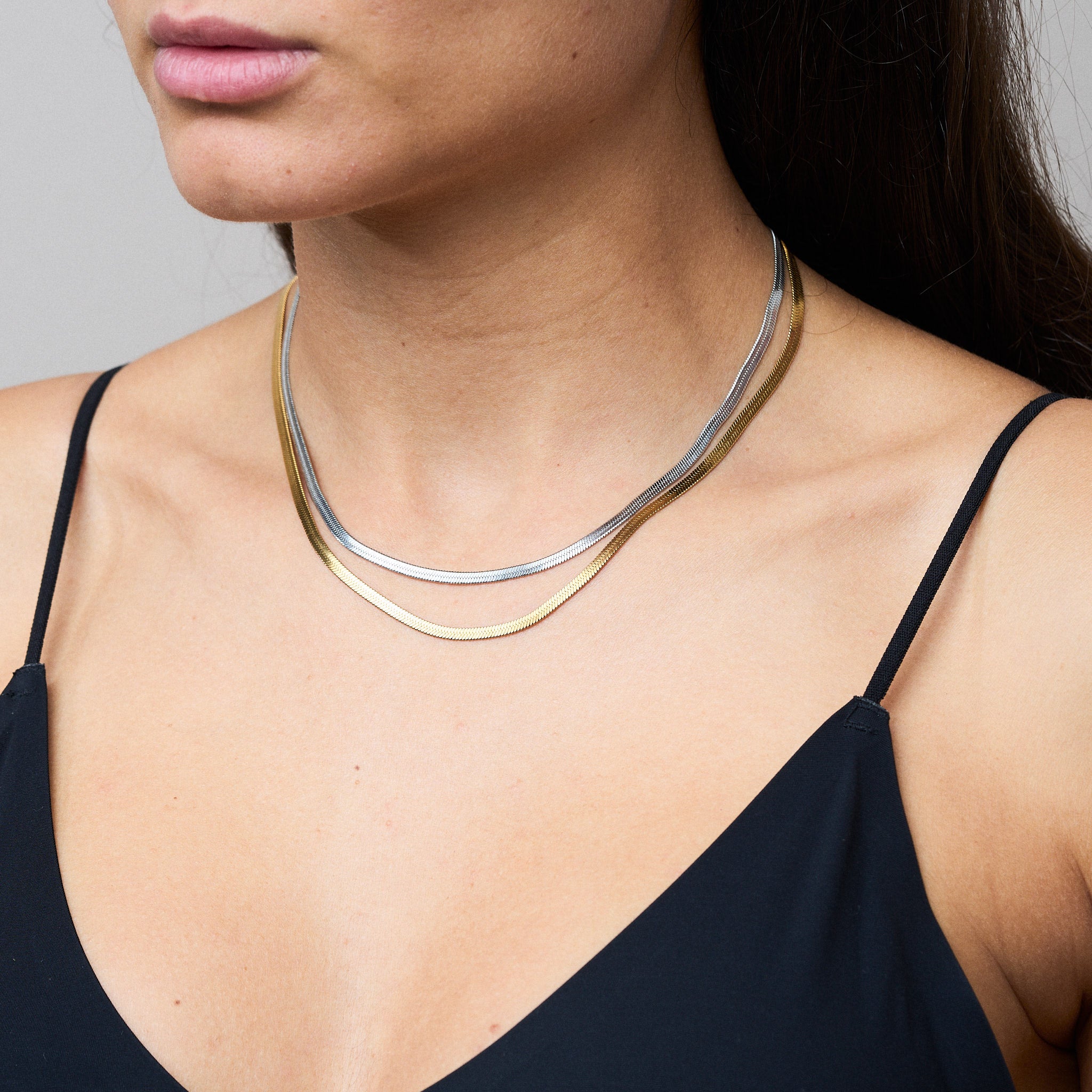 Zwei Snake Mini Ketten in Silber und Gold miteinander verbunden, die sich wie eine zarte Schlange um den Hals legen und im Licht glitzern. Die Bi-Color-Kombination betont den Trend-Look.