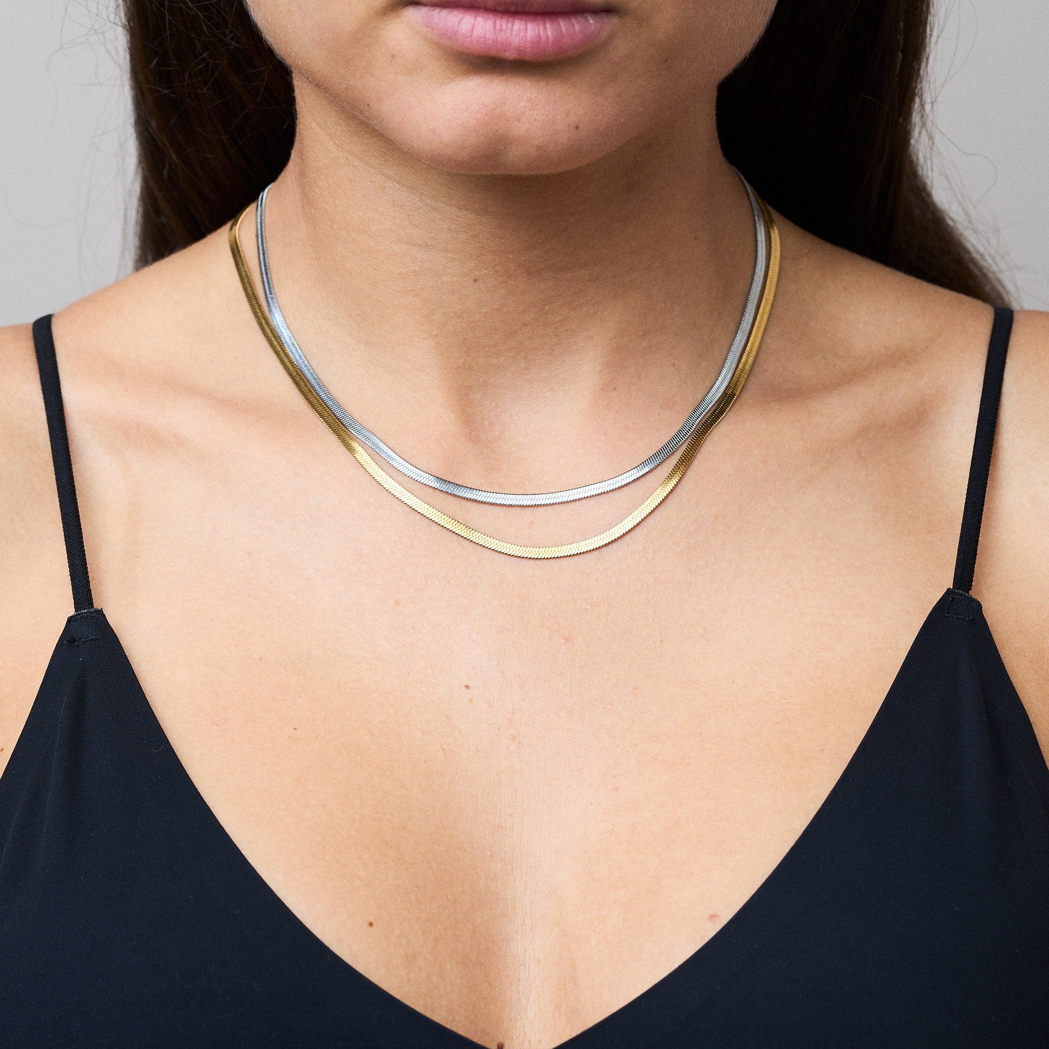 Zwei Snake Mini Ketten in Silber und Gold miteinander verbunden, die sich wie eine zarte Schlange um den Hals legen und im Licht glitzern. Die Bi-Color-Kombination betont den Trend-Look.