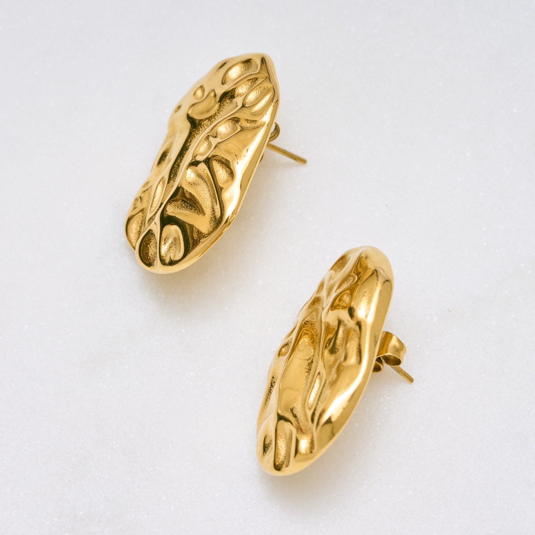 Ein Paar Desert Studs Ohrringe mit gewellter Oberfläche und chunky Design, die Glamour und Eleganz ausstrahlen. Leicht und angenehm zu tragen, perfekt für Abend- oder Alltagslooks.